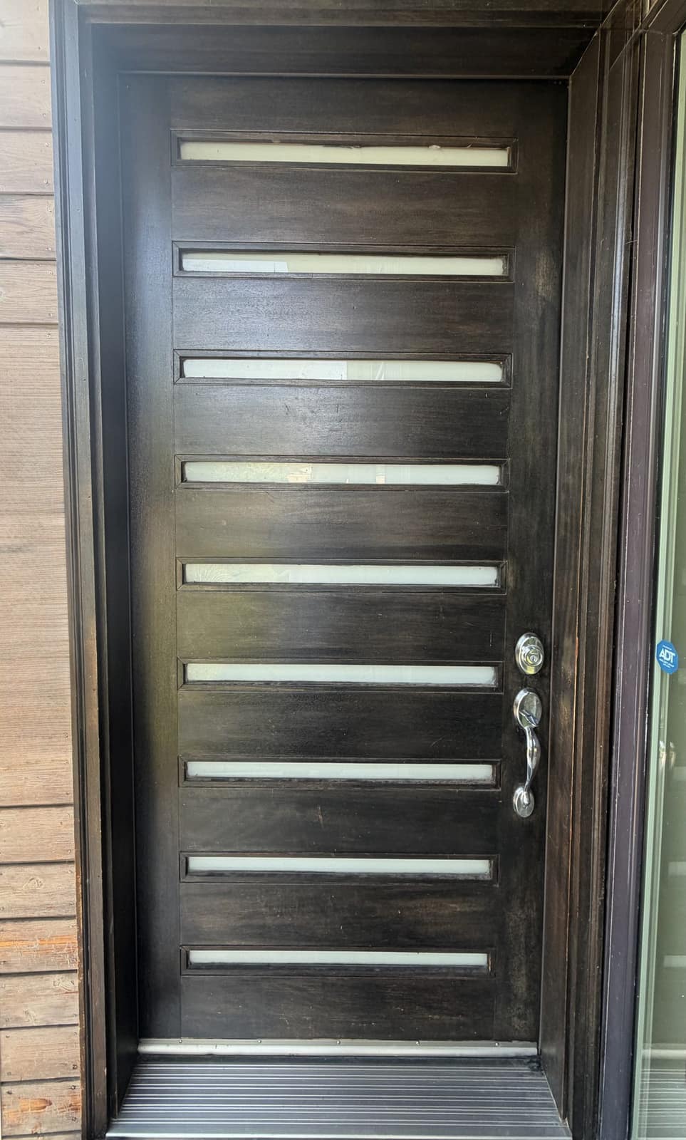 Modern dark-stained entry door with frosted-glass panels installed on a Denver home