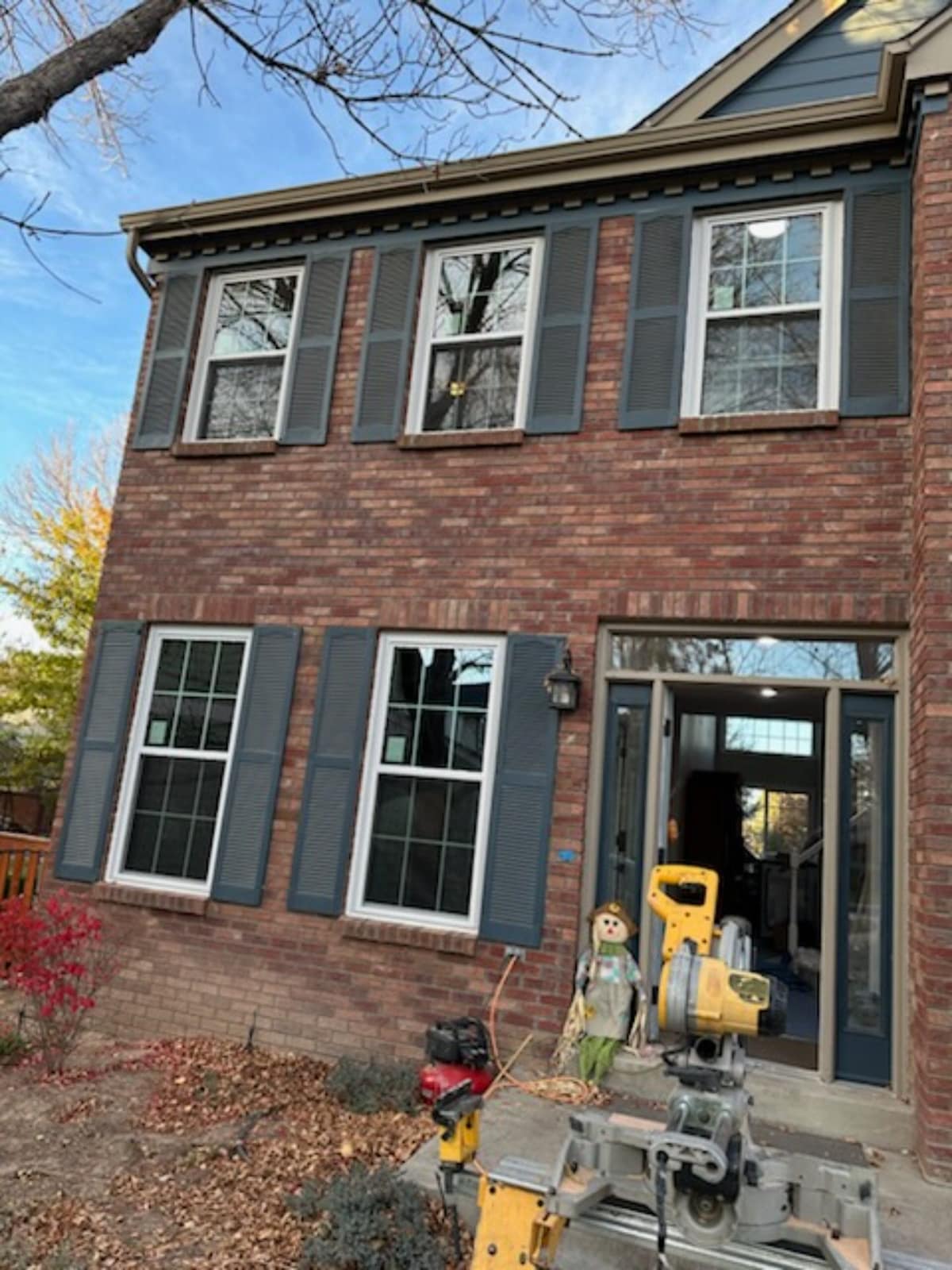 New white double-hung windows with colonial grids on a red brick Colorado home