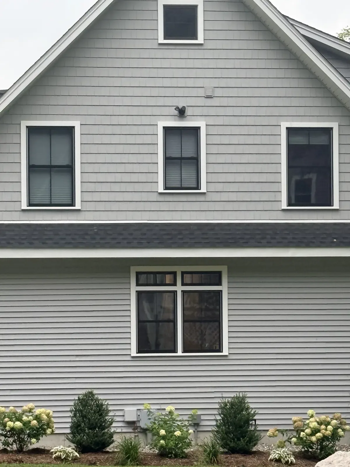 Black-framed replacement windows with white trim across a two-story shingle and lap sided elevation