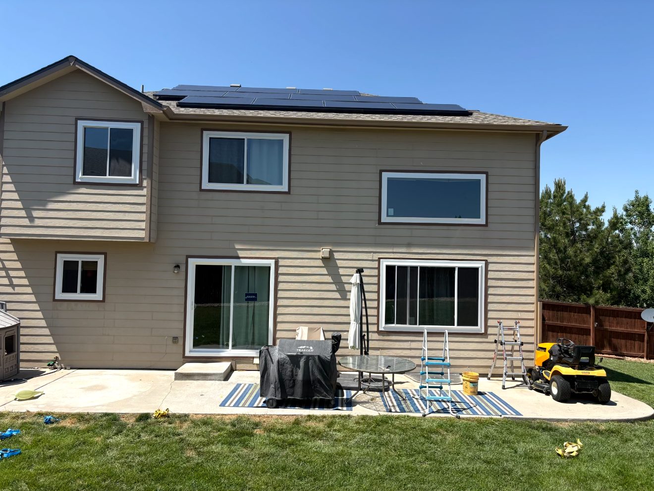 Newly installed white windows and a sliding patio door on the rear of a Colorado home