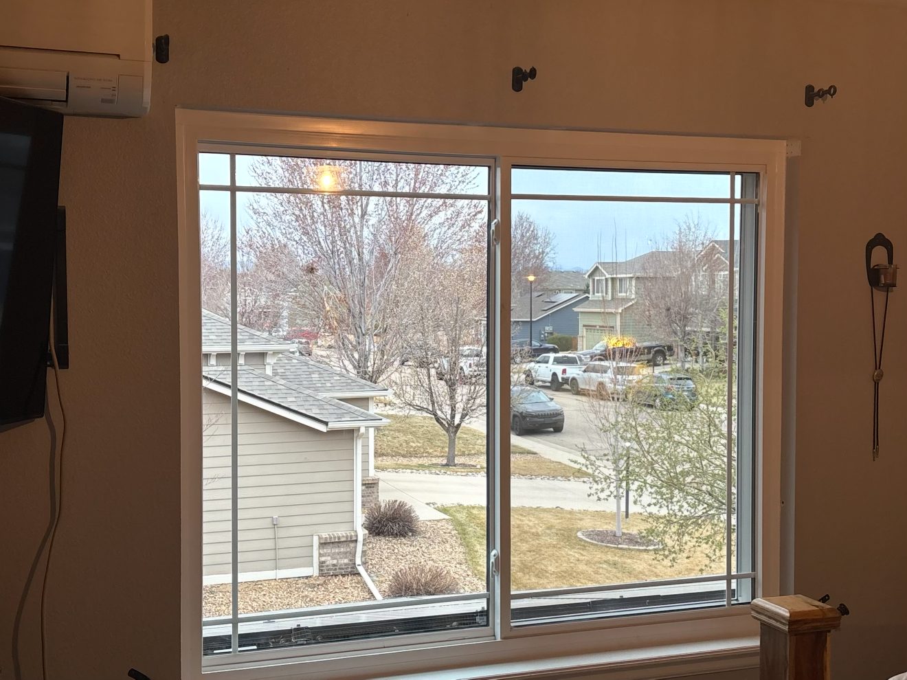 Interior view through a new white slider window with colonial grids overlooking a Colorado neighborhood