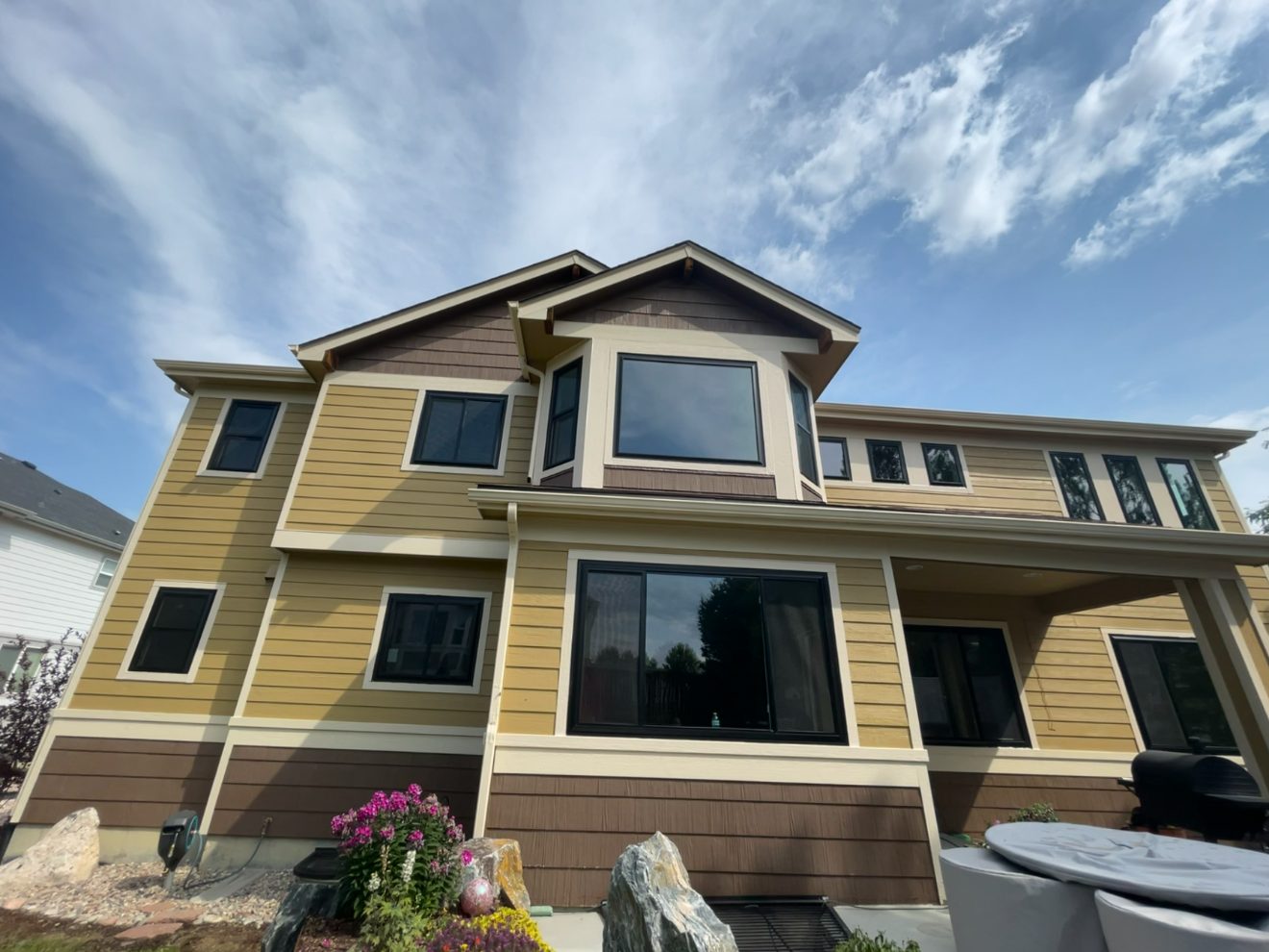 Black-framed replacement windows on a two-story craftsman Colorado home under a blue sky